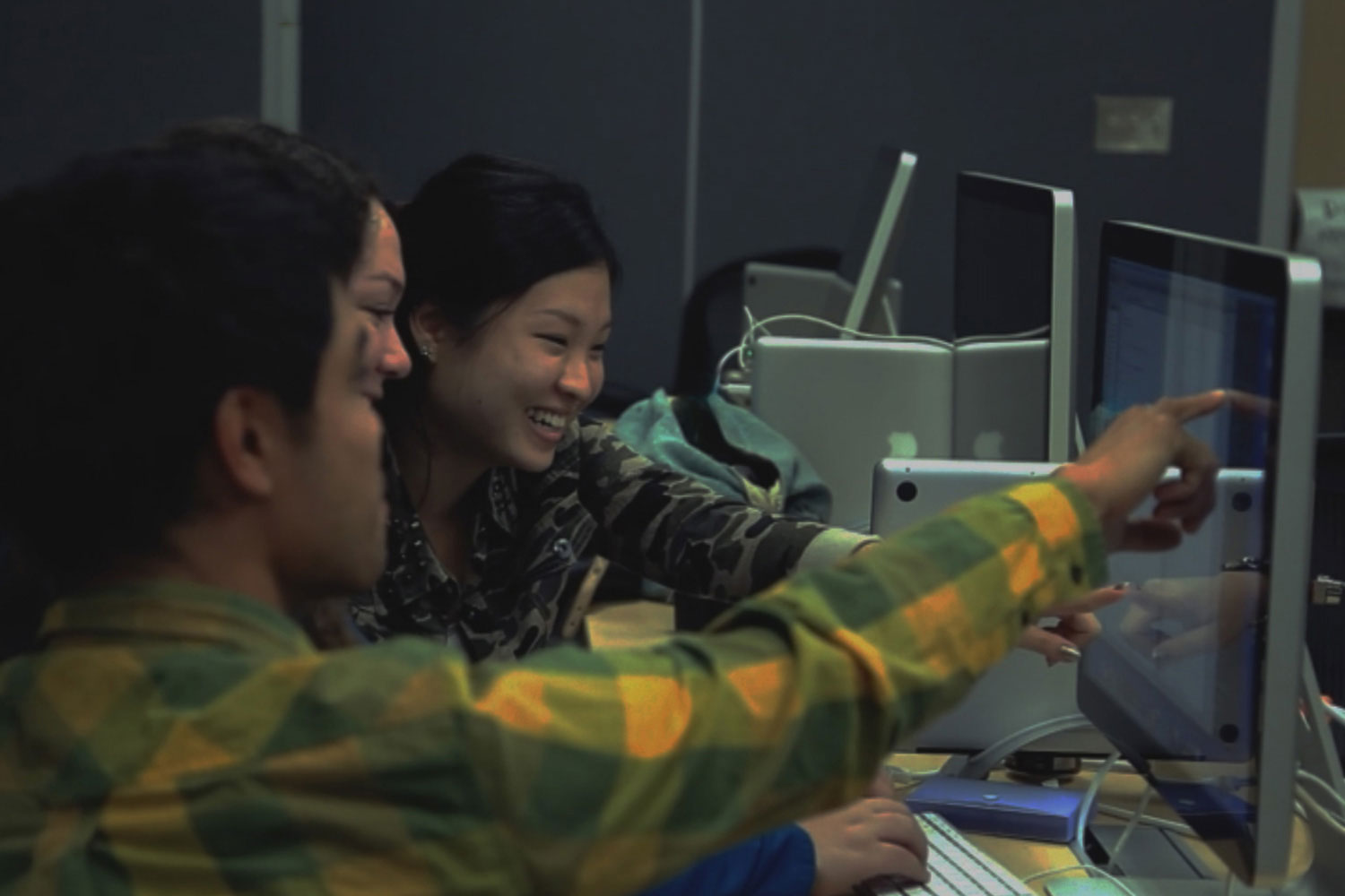 NMA Interface Design - background image of three students working collaboratively on a project pointing to a computer monitor